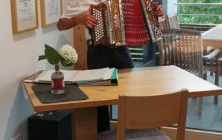 Mann spielt Ziehharmonika hinter einem Holztisch