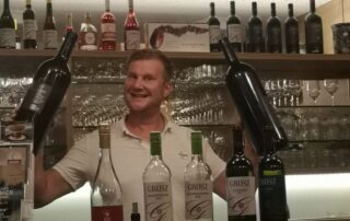 Andreas Grosz mit groszen Weinflaschen in der Hand